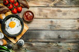 Fried egg in a pan with bread, tomatoes and green onions. photo