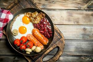 English breakfast.Fried eggs with sausages, bacon and red canned beans. photo