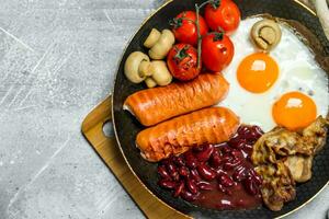 English breakfast. Fried eggs with sausages, bacon and beans. photo