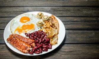 tradicional Inglés desayuno con frito huevos, salchichas y frijoles. foto