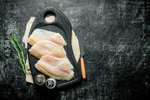 pescado filete en un corte tablero con un cuchillo, especias y Romero. foto