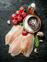 Fish fillet with tomatoes on a branch, spices and oil in a bottle. photo