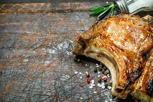 Grilled pork steak on bone with a branch of fresh rosemary. photo