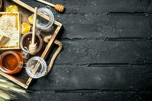 Different kinds of honey on wooden tray. photo