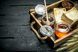 Different kinds of honey on wooden tray. photo