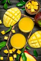 Mango juice and slices of fresh mango on the cutting Board. photo