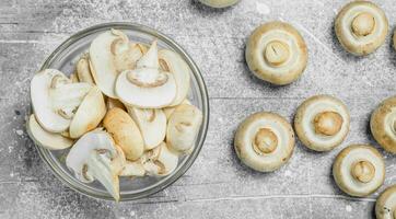 Pieces of fresh mushrooms in the bowl and whole mushrooms. photo