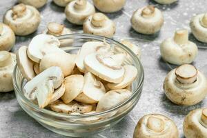 Pieces of fresh mushrooms in the bowl and whole mushrooms. photo