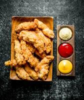 Chicken strips with different sauces. photo