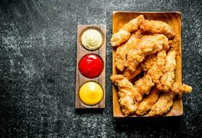 Chicken strips with different sauces. photo