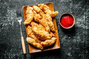 Chicken strips with tomato sauce in bowl. photo