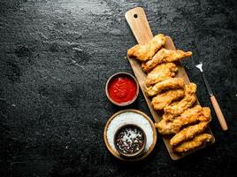 Chicken strips on a cutting Board with spices and sauce. photo