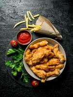 pollo tiras en un cuenco con perejil, Tomates, salsa y francés papas fritas foto