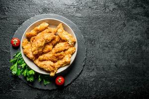 Chicken strips in a bowl with parsley and tomatoes. photo