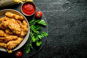 Chicken strips with French fries, greens and tomato sauce. photo