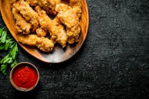 Chicken strips on a plate with parsley and sauce. photo