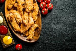 Chicken strips with cherry tomatoes and various sauces. photo