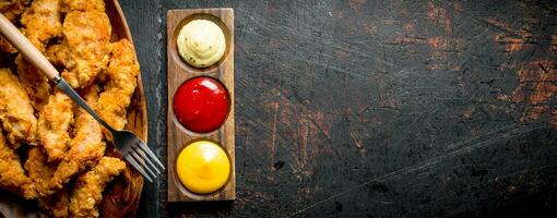 Chicken strips with different sauces. photo