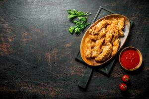 Chicken strips on a cutting Board with parsley and tomato sauce in a bowl. photo