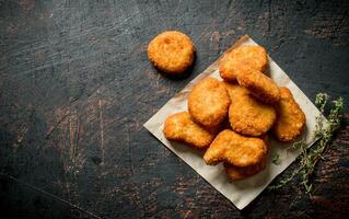 Chicken nuggets on paper with thyme. photo