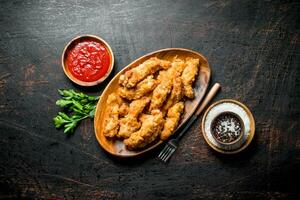 Chicken strips with spices and sauce in bowls. photo