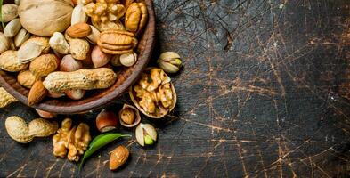 Different kinds of nuts in bowl with leaves. photo