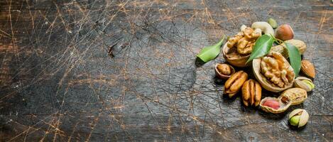 Nuts background. Assortment of different nuts with green leaves . photo