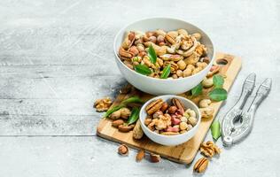 Different types of nuts in bowls with green leaves. photo