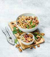 Different types of nuts in bowls with green leaves. photo