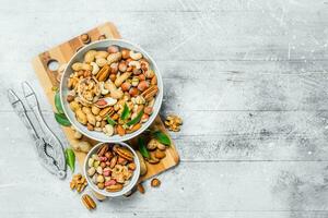 Different types of nuts in bowls with green leaves. photo