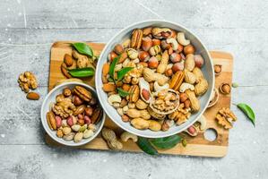 Different types of nuts in bowls with green leaves. photo