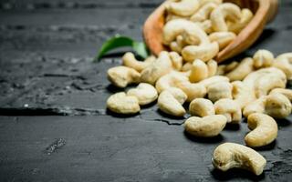 Cashew nuts in a wooden scoop with leaves. photo