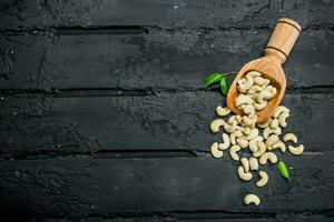 Cashew nuts in a wooden scoop with leaves. photo