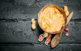 Peanut butter in bowl with wooden spoon . photo