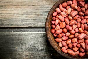 The shelled peanuts in a bowl . photo