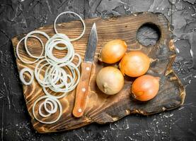 Rings of onions on a cutting Board with a knife. photo