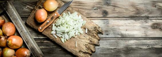 Pieces of onions on a cutting Board with a knife and a whole onion on the tray. photo