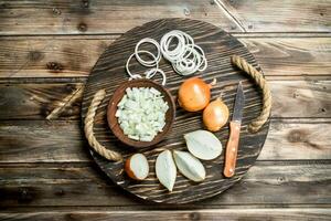 Chopped onions in a bowl and pieces of onions on the tray with a knife. photo