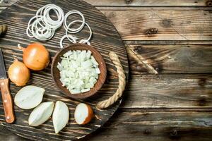 Chopped onions in a bowl and pieces of onions on the tray with a knife. photo