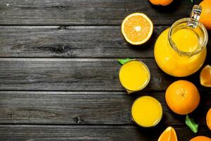 Orange juice in pitcher with fresh oranges. photo