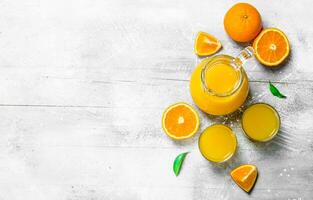 Orange juice in the pitcher and slices of fresh oranges. photo