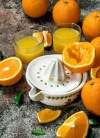 naranja jugo en un vaso y un exprimidor foto
