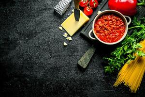 Bolognese sauce in a pan with dry pasta and cheese. photo