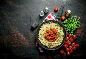 Spaghetti with Bolognese sauce in pan on a napkin with tomatoes and parsley. photo