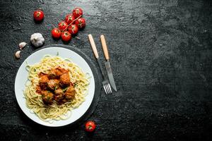 Spaghetti and meat balls on a plate with tomatoes and garlic. photo