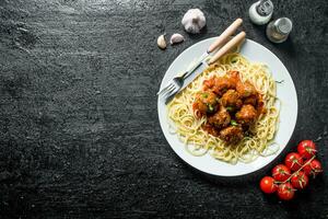 Pasta and meat balls on a plate with tomatoes,garlic and spices. photo