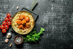 Spaghetti and meat balls in pan with parsley, tomatoes and garlic. photo