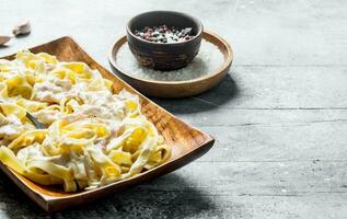 Pasta fettuccine with Carbonara sauce on a plate and spices. photo