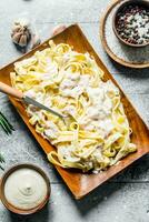 Pasta fettuccine on a plate and sauce in a bowl. photo