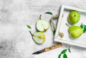 Ripe pear in the tray with a knife. photo